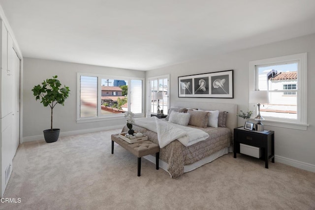 bedroom with light carpet, multiple windows, and baseboards