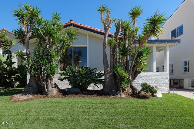 view of side of property featuring a tile roof and a yard