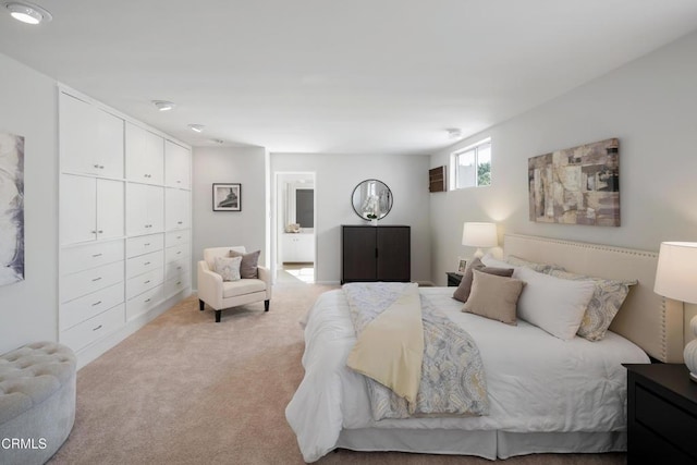 bedroom featuring connected bathroom and light colored carpet