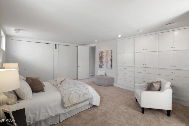 bedroom with light carpet and multiple closets