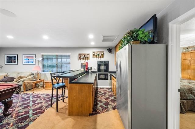 kitchen featuring visible vents, a breakfast bar, dark countertops, open floor plan, and stainless steel fridge with ice dispenser