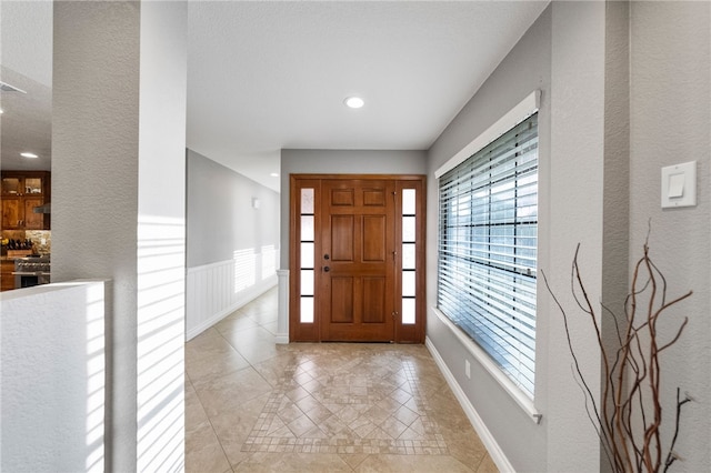 entryway featuring recessed lighting, a wainscoted wall, and baseboards