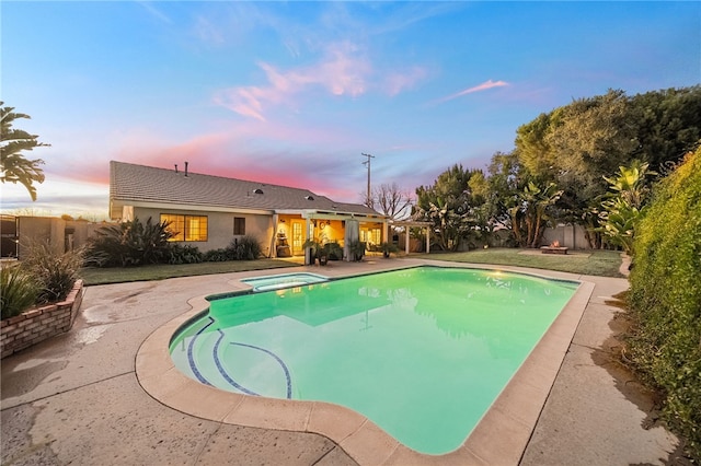 pool at dusk featuring an in ground hot tub, a patio area, and a fenced backyard