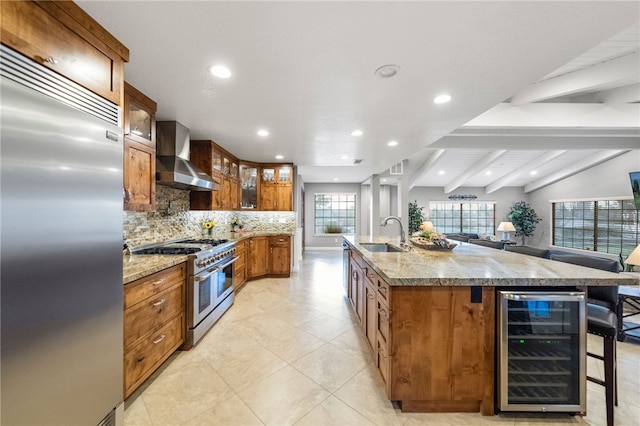 kitchen with beverage cooler, a sink, backsplash, wall chimney exhaust hood, and high end appliances