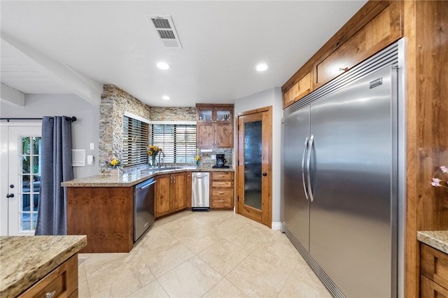 kitchen featuring tasteful backsplash, visible vents, glass insert cabinets, brown cabinets, and appliances with stainless steel finishes