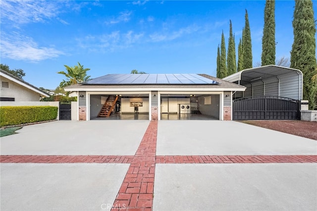 view of front facade with a garage, a gate, brick siding, and roof mounted solar panels