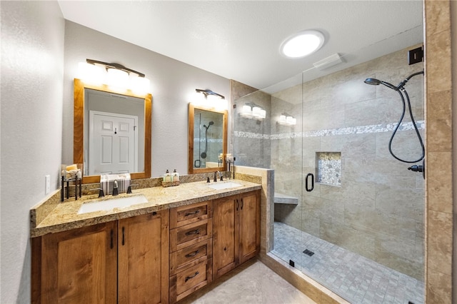 full bathroom featuring double vanity, a stall shower, and a sink