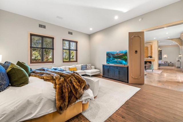 bedroom featuring arched walkways, wood finished floors, visible vents, and recessed lighting