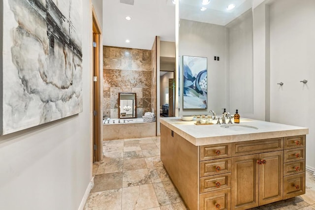 bathroom featuring a garden tub, recessed lighting, a fireplace, vanity, and stone finish floor