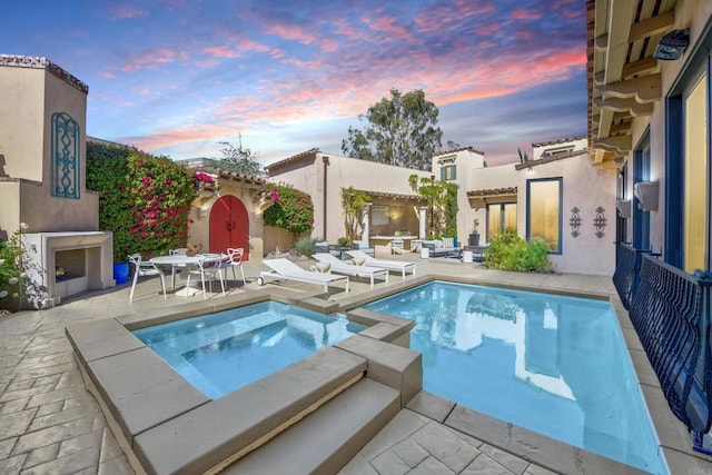 view of pool featuring a pool with connected hot tub, a patio, and an outdoor fireplace