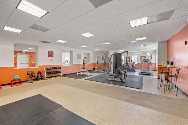 exercise room featuring a drop ceiling and baseboards