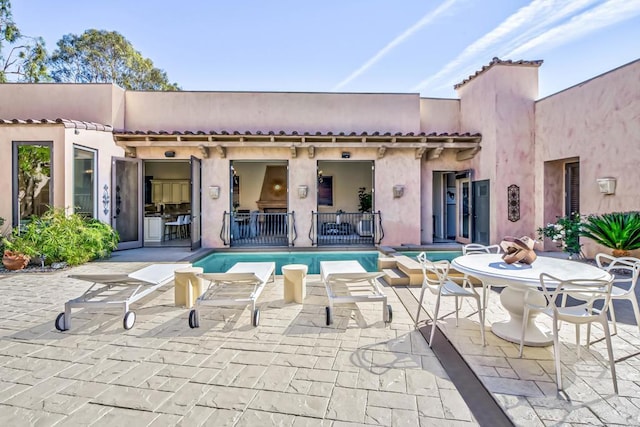 back of house featuring a patio, stucco siding, and an outdoor pool