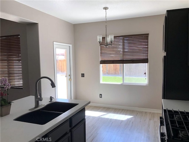 kitchen featuring an inviting chandelier, a sink, light wood-style flooring, and a healthy amount of sunlight