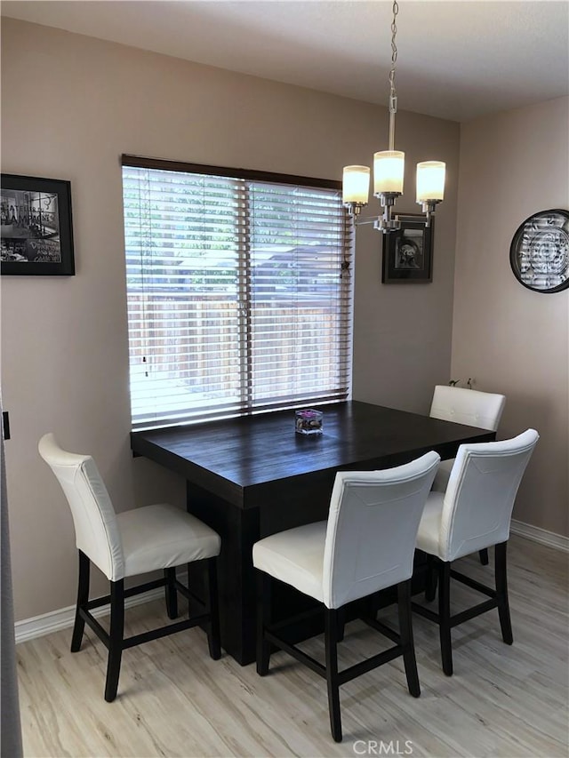 dining area featuring baseboards, light wood-style floors, an inviting chandelier, and a healthy amount of sunlight