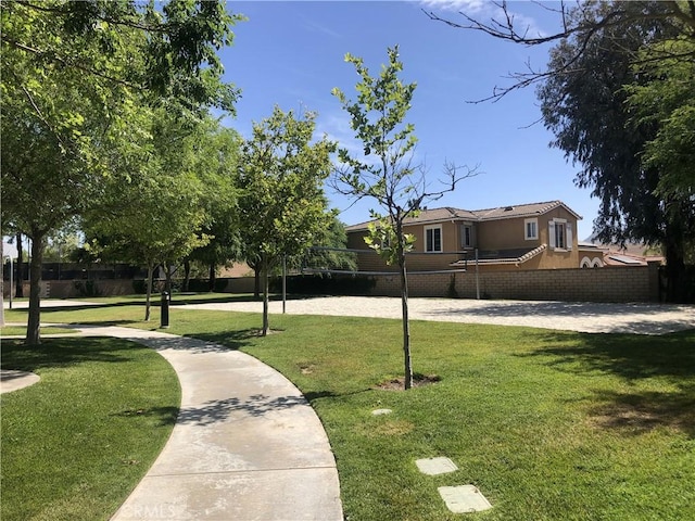 view of home's community featuring fence, a lawn, and volleyball court