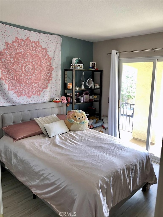 bedroom with access to exterior, a textured ceiling, and wood finished floors