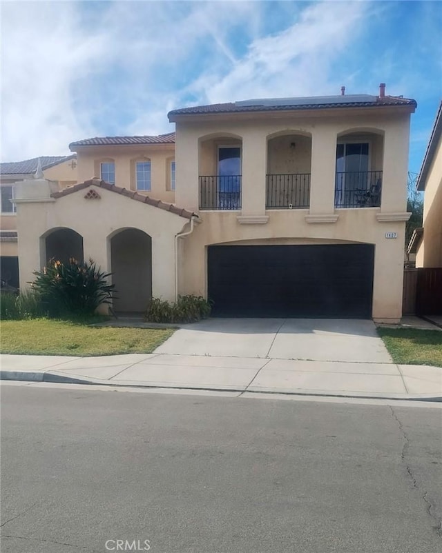 mediterranean / spanish-style house featuring a garage, a tile roof, driveway, and stucco siding