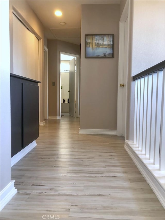 corridor with light wood-style flooring and baseboards