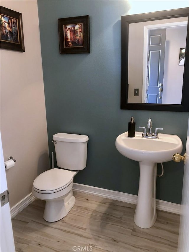 bathroom with toilet, baseboards, and wood finished floors