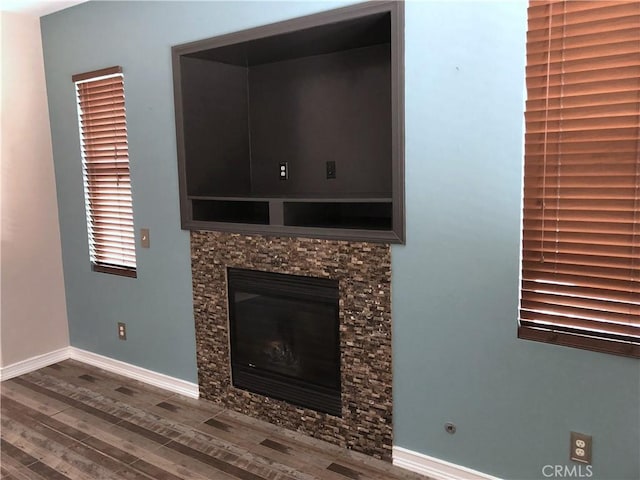 details with a stone fireplace, baseboards, and wood finished floors