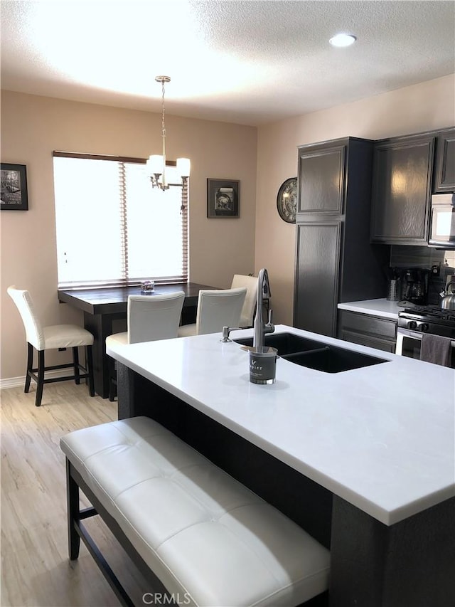 kitchen featuring a breakfast bar, light countertops, a sink, a textured ceiling, and light wood-type flooring