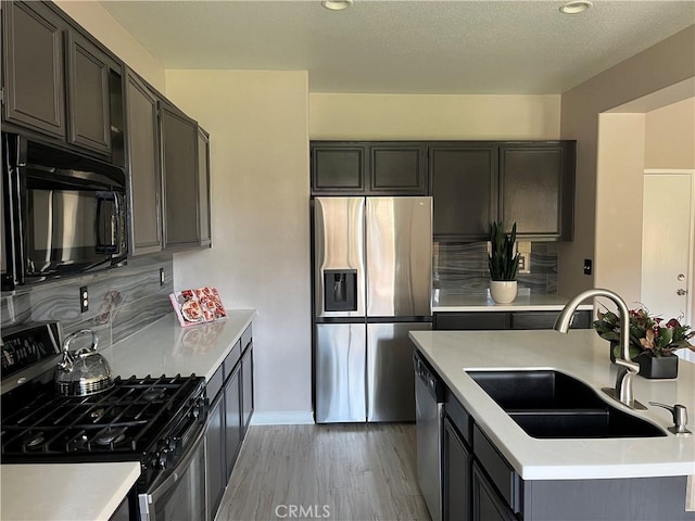 kitchen featuring light wood finished floors, appliances with stainless steel finishes, light countertops, and a sink