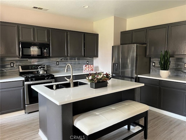 kitchen featuring a sink, visible vents, light countertops, appliances with stainless steel finishes, and decorative backsplash