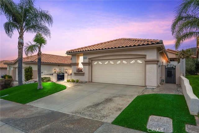 mediterranean / spanish home with a gate, stucco siding, concrete driveway, a garage, and a tiled roof