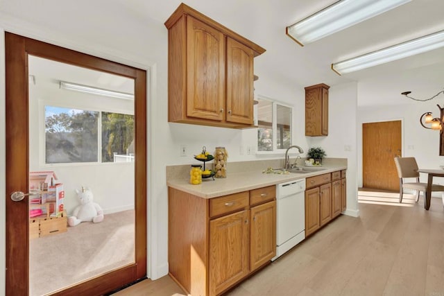 kitchen featuring light countertops, light wood-style flooring, brown cabinetry, white dishwasher, and a sink