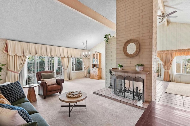 living area featuring vaulted ceiling with beams, a textured ceiling, a fireplace, and ceiling fan with notable chandelier