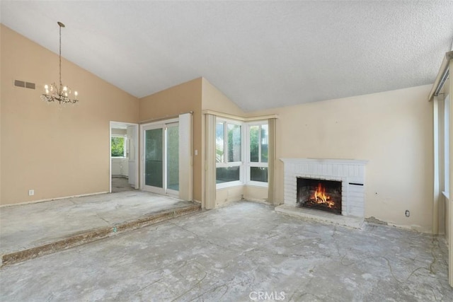 unfurnished living room with a healthy amount of sunlight, an inviting chandelier, a fireplace, and visible vents