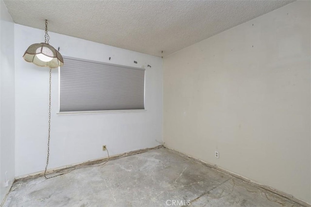 unfurnished room with a textured ceiling and unfinished concrete floors