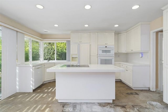 kitchen featuring white appliances, a kitchen island, tile counters, and white cabinets