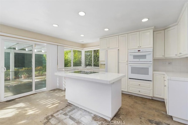 kitchen featuring tile countertops, double oven, white cabinets, and a center island