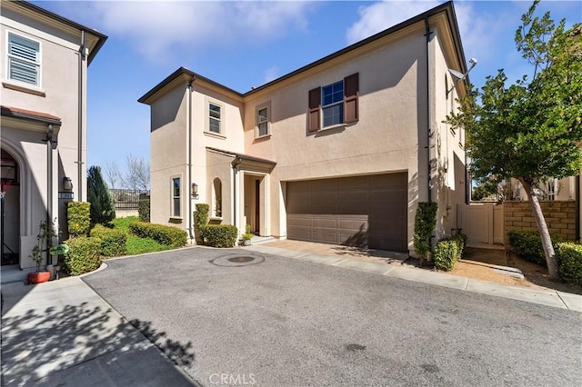 view of front of home with a garage, fence, driveway, and stucco siding