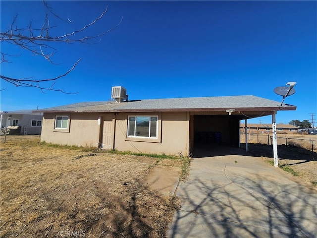 view of front of property with central AC, fence, concrete driveway, stucco siding, and a carport