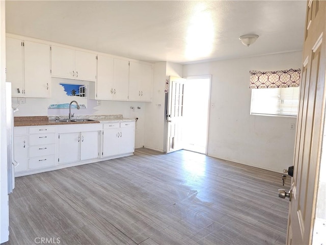 kitchen with light wood-style flooring, white cabinets, a sink, and light countertops