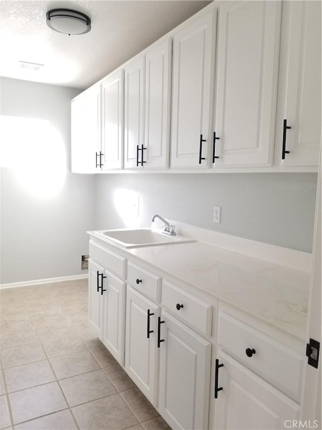 washroom featuring light tile patterned flooring, a sink, visible vents, and baseboards