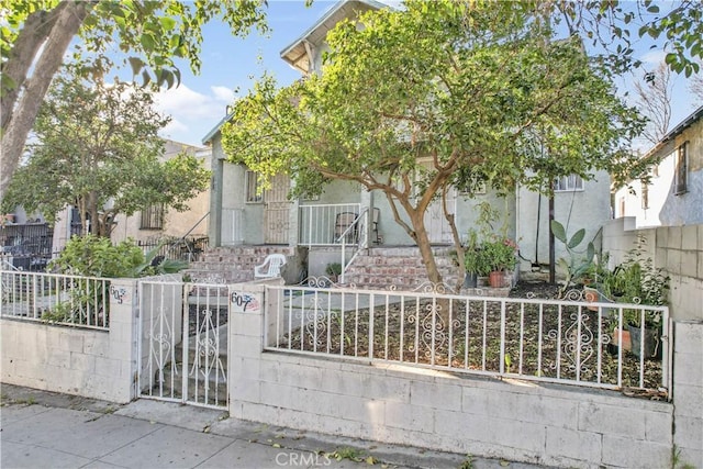 view of property hidden behind natural elements featuring a fenced front yard and a gate