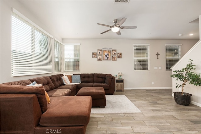 living area featuring baseboards, visible vents, ceiling fan, wood tiled floor, and stairs