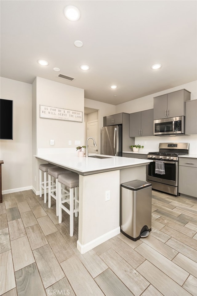 kitchen featuring stainless steel appliances, light countertops, a sink, a peninsula, and a kitchen breakfast bar