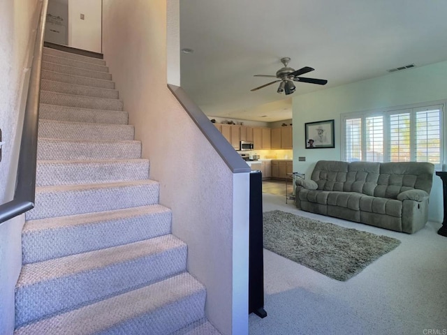 stairway with carpet, ceiling fan, and visible vents