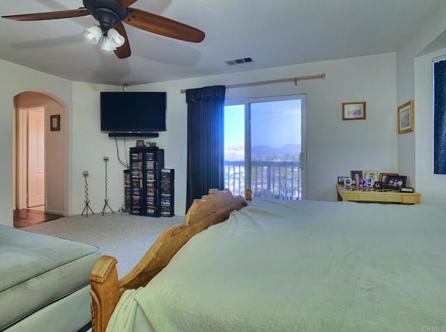 bedroom featuring carpet, visible vents, arched walkways, and a ceiling fan