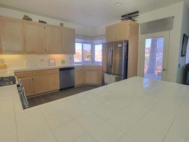 kitchen featuring dark wood-style floors, appliances with stainless steel finishes, tile counters, and light brown cabinetry