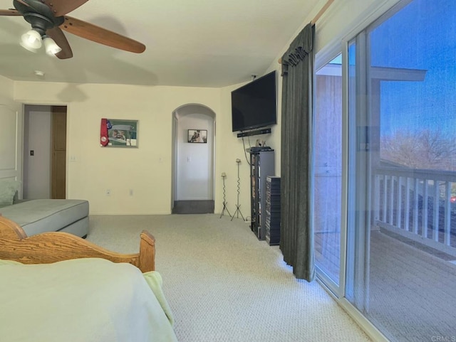 bedroom featuring arched walkways, access to outside, a ceiling fan, and light colored carpet