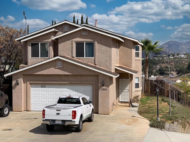 view of front facade featuring a garage, fence, concrete driveway, and stucco siding