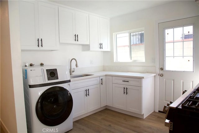 clothes washing area with light wood-type flooring, washer / dryer, and a sink