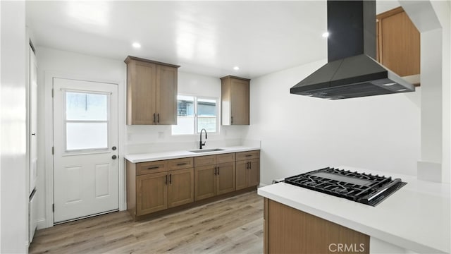 3659 W 110th St, Inglewood, CA 90303 - kitchen featuring wall chimney exhaust hood, stovetop, light wood-type flooring, light countertops, and brown cabinets