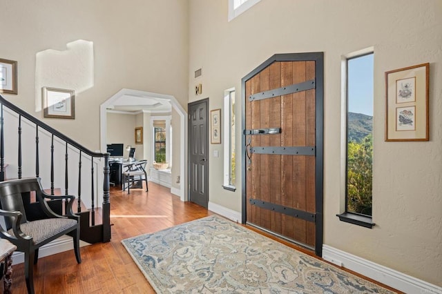 entryway with baseboards, a high ceiling, stairway, and wood finished floors