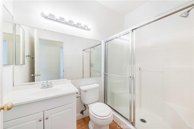 full bath with toilet, a shower stall, wood finished floors, and vanity